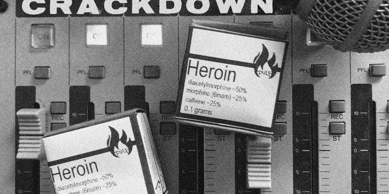 Image: Two boxes of tested and labeled heroin, distributed by the Drug User Liberation Front, and a microphone rest on a mixing board. (Photo: Garth Mullins)
